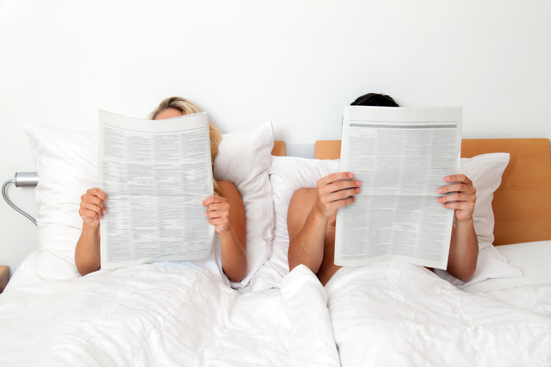 Paar liest Zeitung im Bett